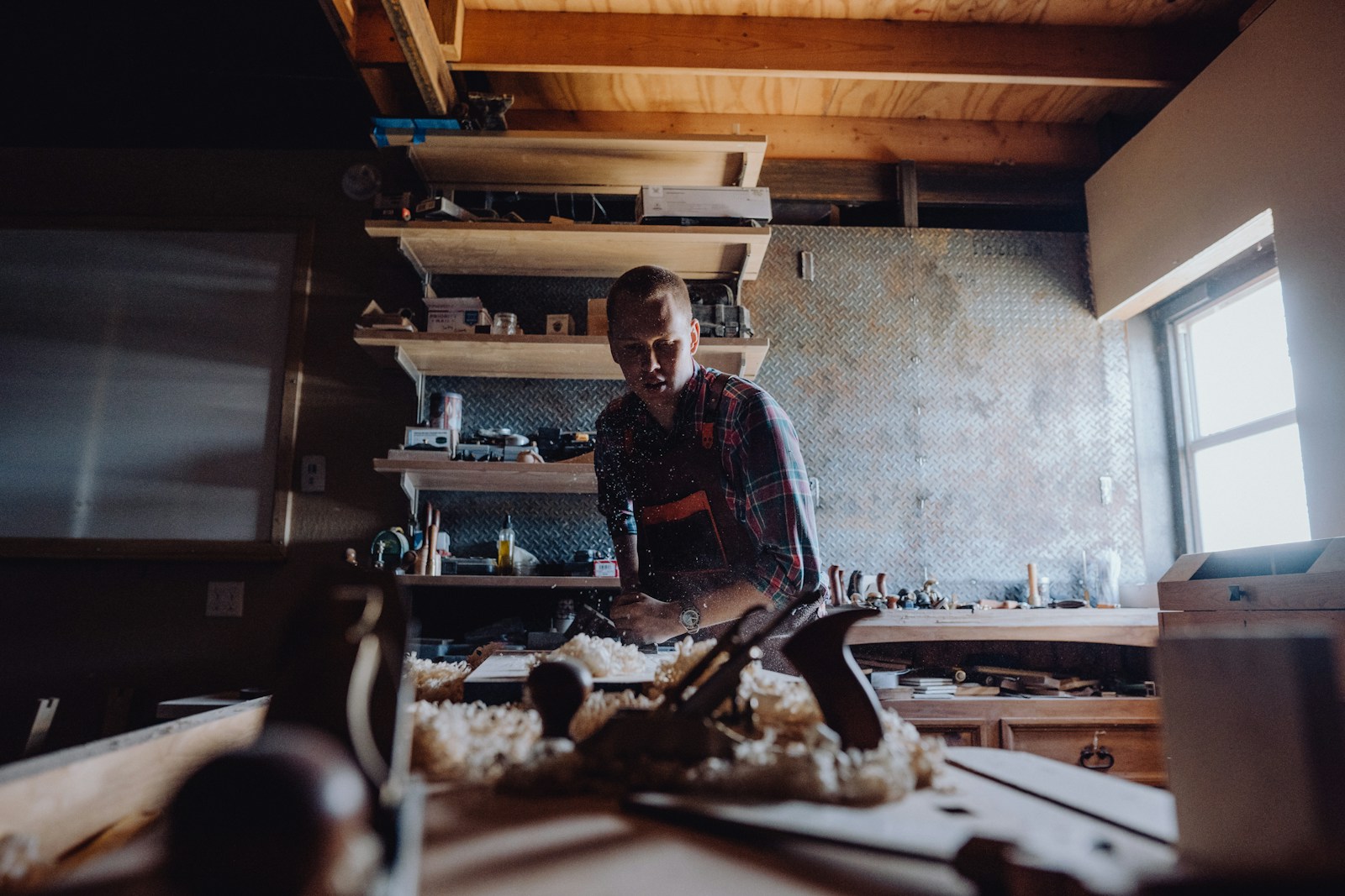 A woodworker shaping a part at a bench in a cabinet shop